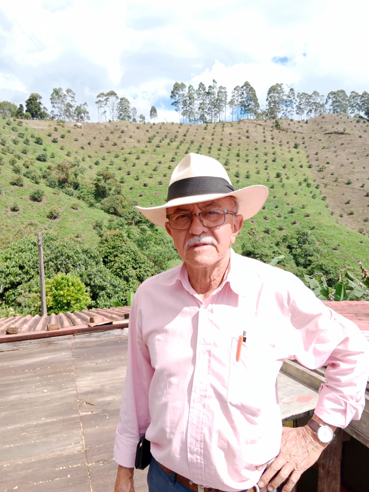 Don Norber con sombrero frente a los cafetales de la ladera